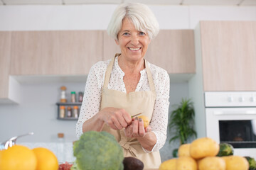 mature woman cooking vegetables in kitchen