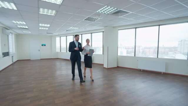 Couple of top managers goes to a business meeting, the interior of a white office space with panoramic windows, a walk through the office inside a skyscraper.