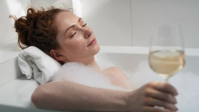 Caucasian redhead woman taking a bath and drinking wine. Shot with RED helium camera in 4K.  