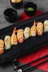 Sushi set of various products on a black stone plate. Blur background and selective focus
