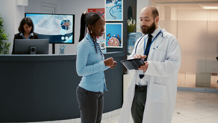 Male physician talking to african american patient about healthcare, showing medical diagnosis...