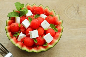 Watermelon Feta salad in watermelon basket with wooden table background.Fresh and healthy Italian summer salad.Top view.Copy space