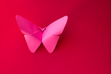 Pink paper butterfly origami isolated on a red background