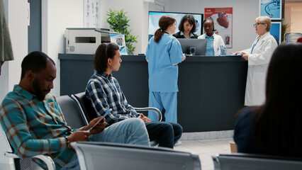 Asian patient in hospital waiting room filling in medical checkup report to attend consultation with medic. Using form to do healthcare examination at appointment, waiitng area lobby.