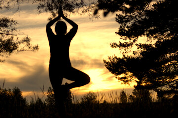 silhouette of a woman doing yoga exercises on sunset