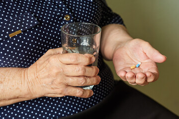 Elderly woman with a glass of water is going to take pills
