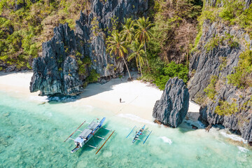 View from above, stunning aerial view of a person on the Entalula Beach, a white sand beach bathed by a crystal clear water. Entalula island, Bacuit Bay, El Nido, Palawan, Philippines.