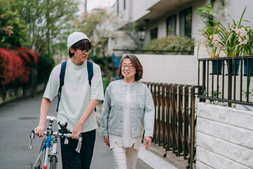 住宅街を歩く祖母と自転車を押す10代の少年