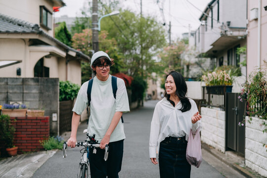 買い物から小さな住宅街を歩いて帰る母親と10代の息子 - Powered by Adobe
