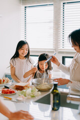 Obraz na płótnie Canvas パスタを調理する祖母と孫娘たち