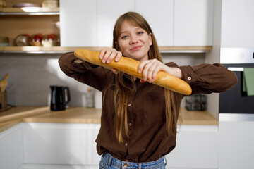 Young woman with French baguette in her hands in the kitchen