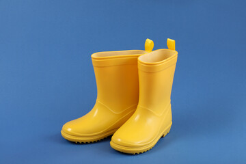 Pair of yellow rubber boots on blue background
