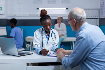 Medic specialist discussing with sick senior patient about disease symptoms and consultation appointment while checking medication side effects. Healthcare practitioner expert recommend man recovery - obrazy, fototapety, plakaty