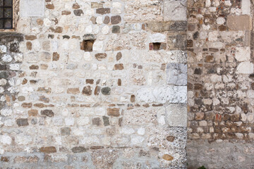 Alte Steinmauer Fassade. Alte Mauer einer Kirche aus rechteckig gehauenen Natursteinen. Old stone wall facade. Old wall of a church made of natural stones.