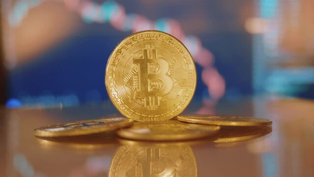 The obverse of shining gold bitcoin coin with capital B letter, placed vertically, on blurry digital currency transaction chart in the background, close up shot.