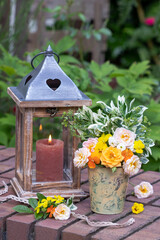 Dekoration mit Rosenstrauß und vintage Laterne im Garten