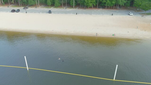 aerial footage of the silky brown sand of the beach surrounded by rippling lake water and lush green trees, grass and plants at Proctor Landing Park at Lake Acworth in Acworth Georgia USA