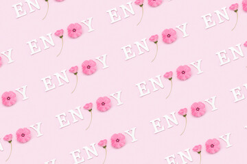 Enjoy. Creative inspirational pattern made with motivational quotes from white letters and beauty natural flowers on pink background