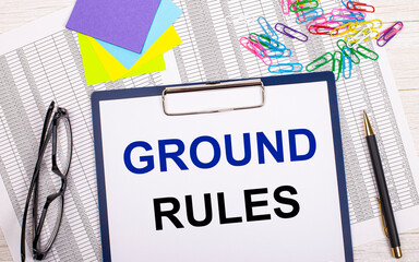 A notepad with the text GROUND RULES, a pen, reports, bright stickers, paper clips and glasses lie...