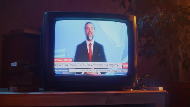 Close Up Footage of a Dated TV Set Screen with Breaking News Report. Handsome Middle Aged Anchorman Reads Important News on Live Television Broadcast. Nostalgic Retro Nineties Technology Concept.