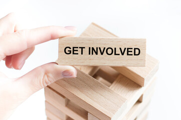 Cropped view of hands holding wooden cube with GET INVOLVED lettering on work table. Top view