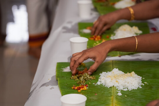 Traditional South Indian food served on plantain leaf in a row. Rice, sambar, salads, etc. Eating with hands.
