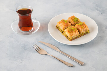 Baklava pistachio on a white plate with Turkish tea	