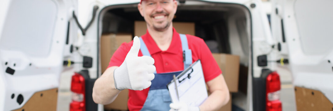 Cheerful delivery service worker show thumbs up gesture in front of car