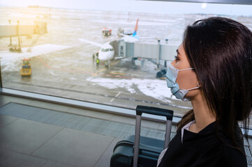 Girl at the airport window waits for a flight