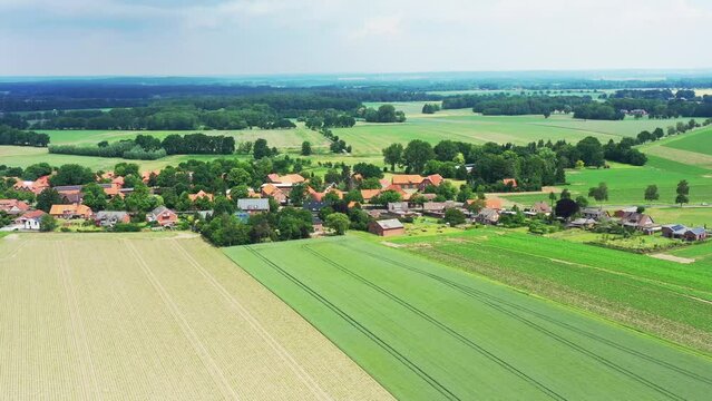Aerial view of a village in the flat landscape of northern Germany with farmland in front of it