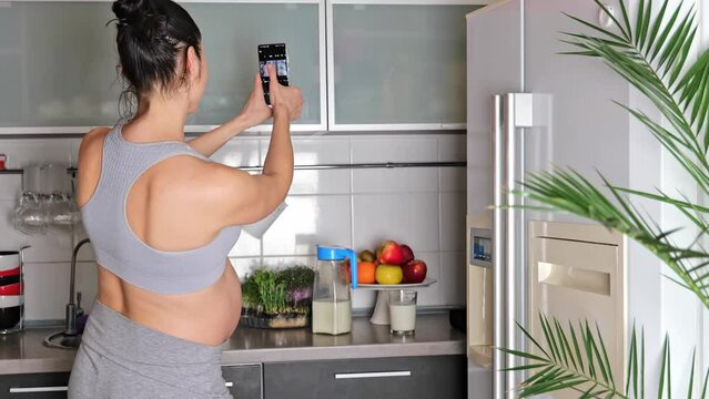 Happy cheerful pregnant woman taking selfie with smartphone mobile at home kitchen. Motherhood. Technology. Expectation. Blogging content, communication concept