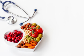 Cholesterol diet concept. Healthy food in heart shaped dish with stethoscope