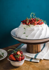 summer dessert of Pavlova with strawberries and whipped cream on blue background