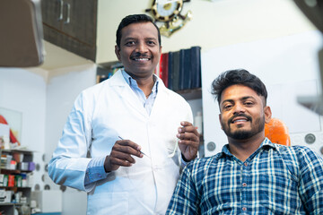 Portrait shot of happy smiling patient with dental doctor or dentist at hosptial looking at camera - concept of oral care, diagnosis and treatment