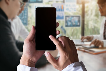 Business - technology and office concept - Hand holding mobile phone with blank screen in office.