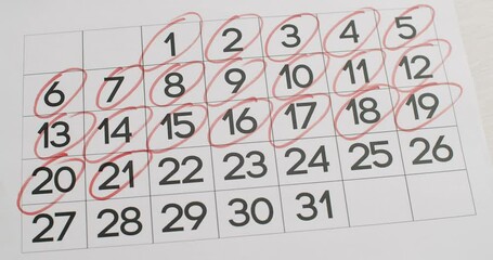 Man's hand Write down the 21,22,23,24,25,26,27,28,29,30,31 day on the paper calendar using a red pen. Very important date in the calendar. Signing a day on a calendar. Calendar date of the month cut.