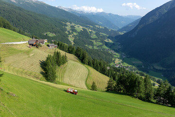 Mountainous landscape with agricultural vehicle for haymaking. Austria