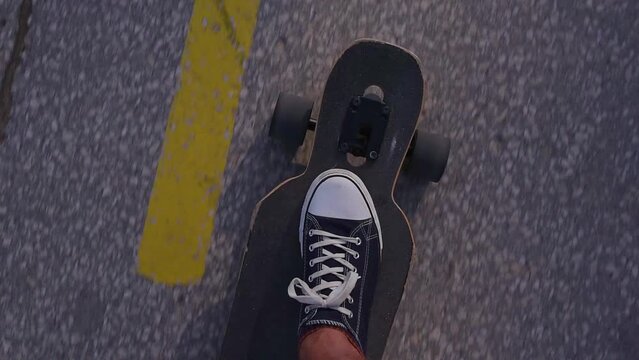 Riding longboard close-up, male feet in sneakers