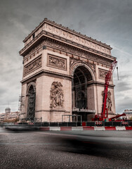 View of the Arc de Triomphe in Paris as vehicles speed by.