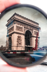 View of the Arc de Triomphe in Paris as vehicles speed through a filter.