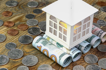 House on top of american dollars banknotes rolled into tube and many us coins. Home cash and saving of financial assets for investment of real estate and property. - 509765206