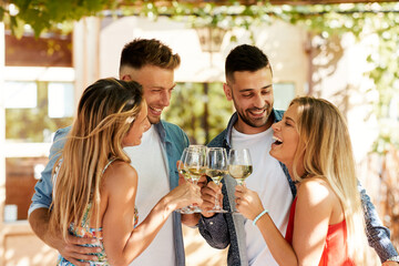 Group of young people enjoy and drink white wine in backyard during a summer sunny day