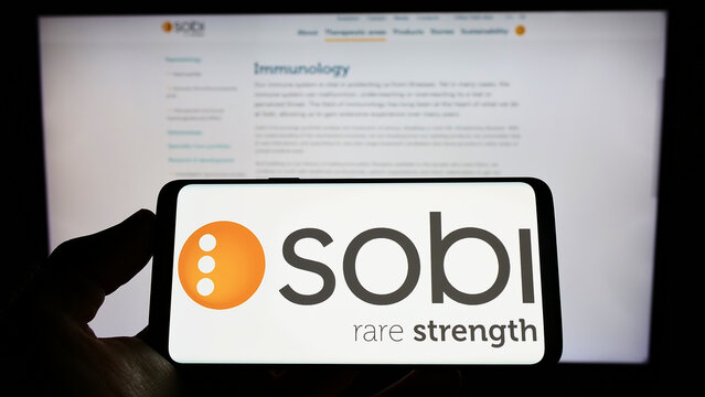 Stuttgart, Germany - 06-06-2022: Person holding smartphone with logo of company Swedish Orphan Biovitrum AB (Sobi) on screen in front of website. Focus on phone display.