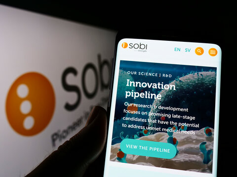 Stuttgart, Germany - 06-06-2022: Person holding cellphone with website of company Swedish Orphan Biovitrum AB (Sobi) on screen in front of logo. Focus on center of phone display.