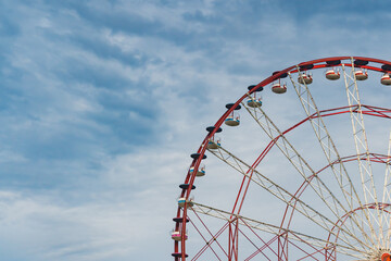 Part Of Red Ferris Wheel Over Beautiful Blue Sky With Soft White Clouds. High quality photo