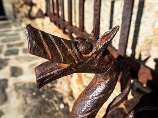 imagen detalle de la parte inferior de una verja de hierro forjado a mano con una cabeza de dragón