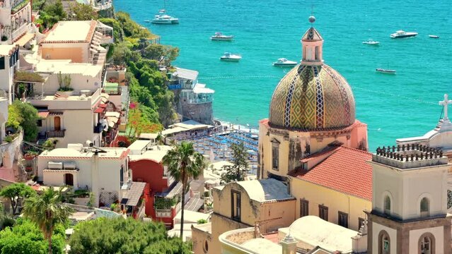 Street scape of Positano, located on the Tyrrhenian sea coast, Italy. Rows of residential buildings, church, greenery, beach with resting people