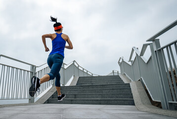Healthy lifestyle fitness sports woman runner running up stairs on seaside trail