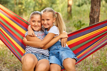 Kids relax in colorful rainbow hammock. cation. Children relaxing.