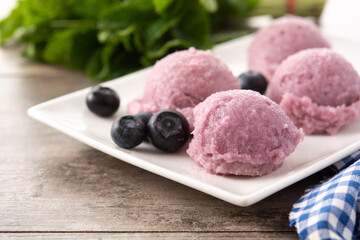Blueberry ice cream scoops on wooden table	